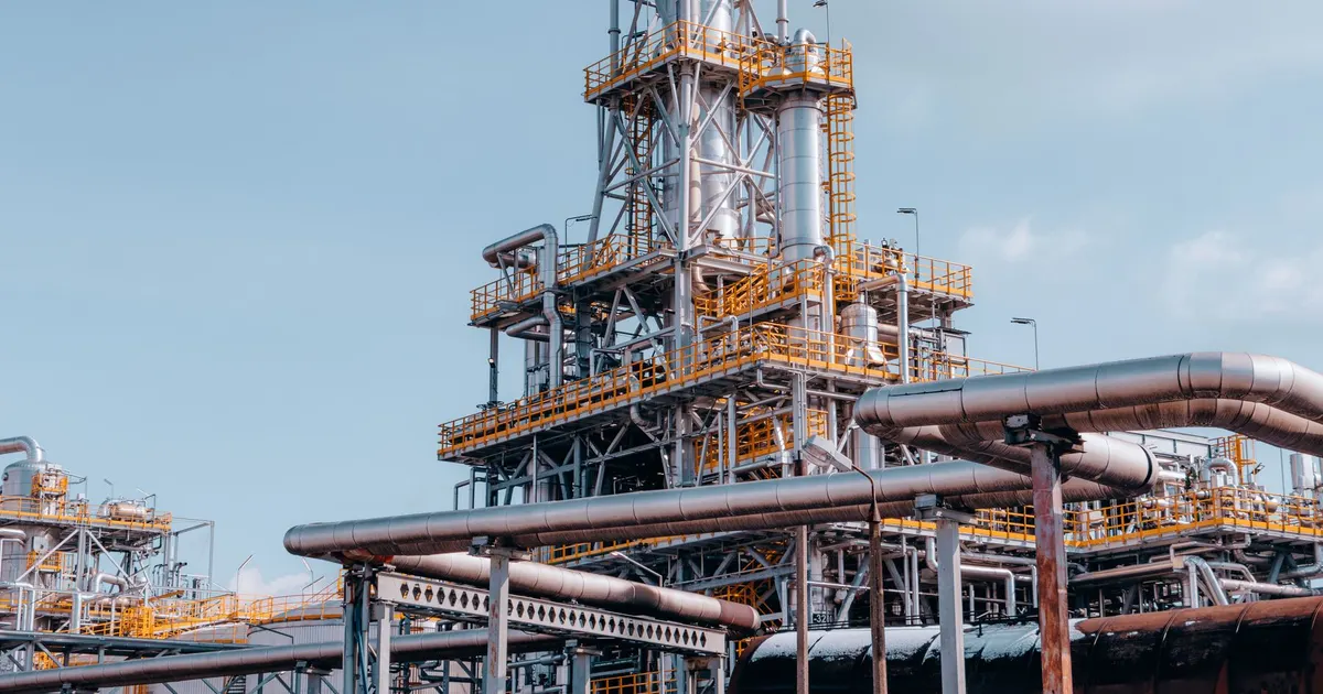 Process plant tower with platforms and a network of pipes under a blue sky, a generic view of the kind of high-temperature process plant where Incoloy 800H is used
