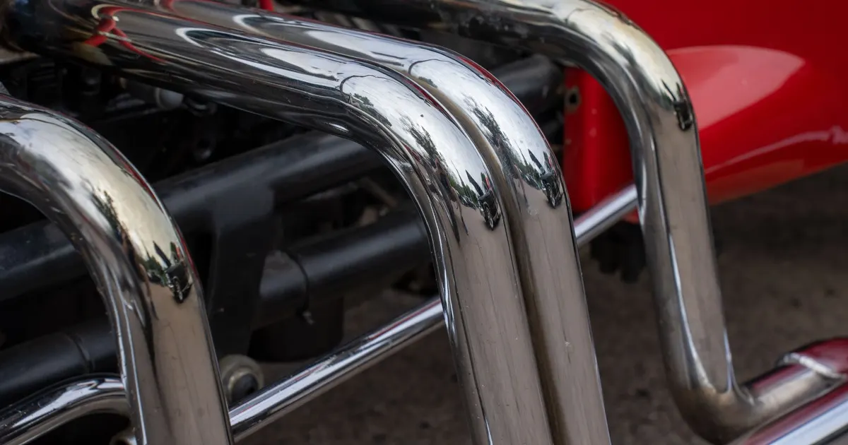 Polished chrome-finish exhaust header pipes curving away from an engine in a car, a generic view of exhaust headers