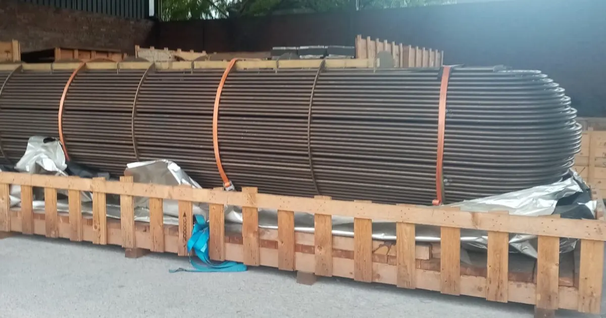 Long tube bundle of a shell and tube heat exchanger resting on wooden supports before assembly