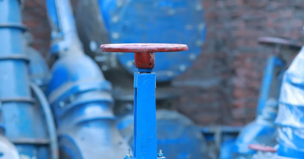 Large blue gate valves with raised stems and handwheels standing in a warehouse, a generic view of industrial valves